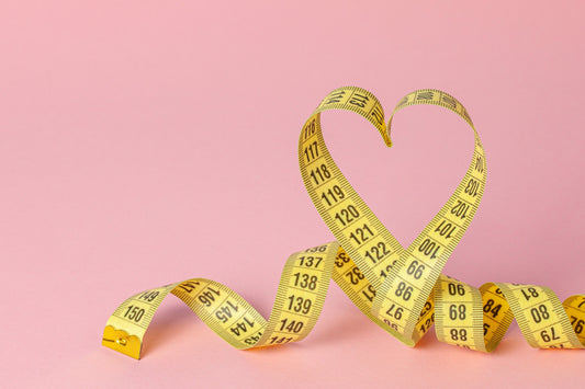 Yello tape measure coiled up to resemble a heart shape against a pink background